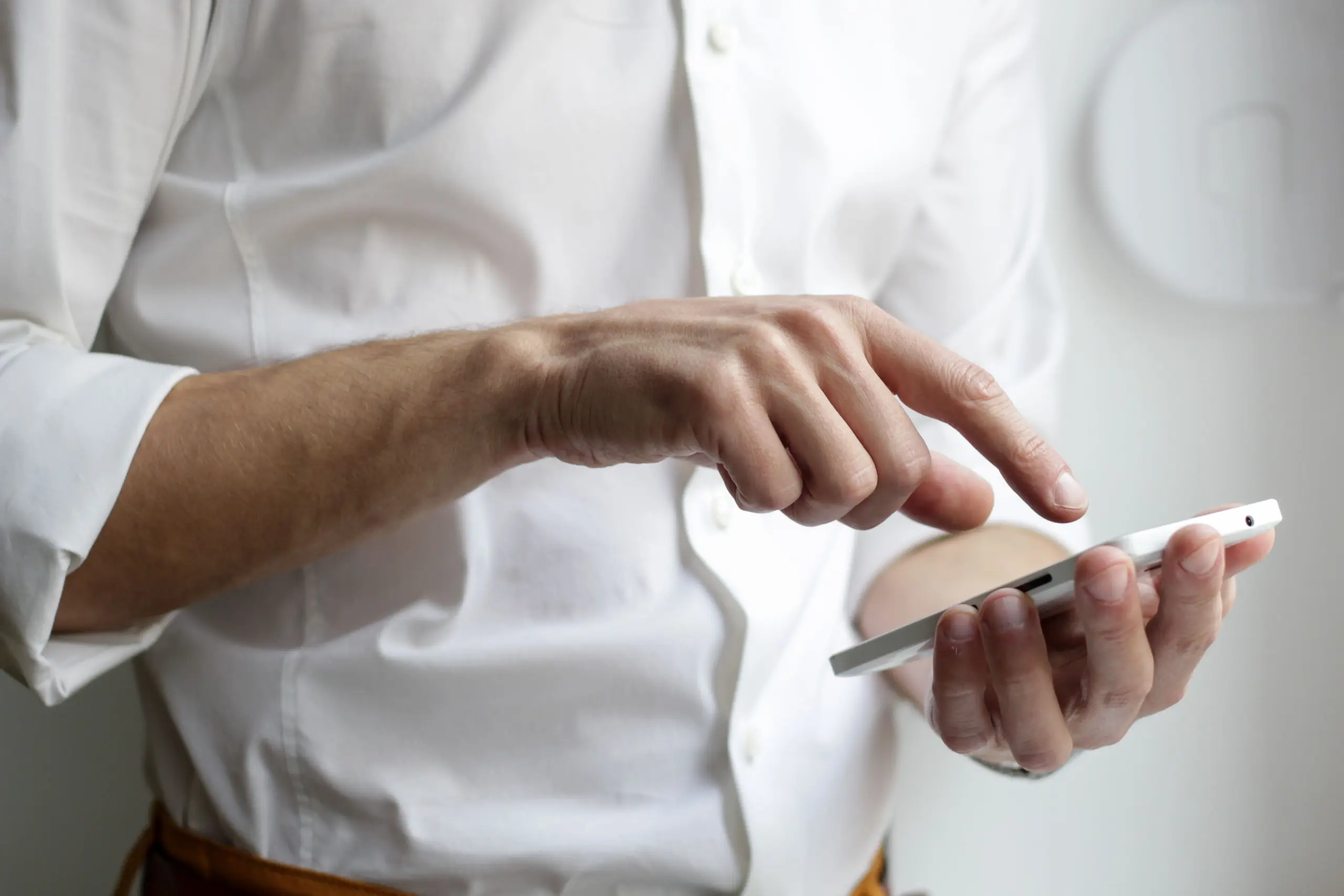A man wearing a white shirt searching for something on his smartphone