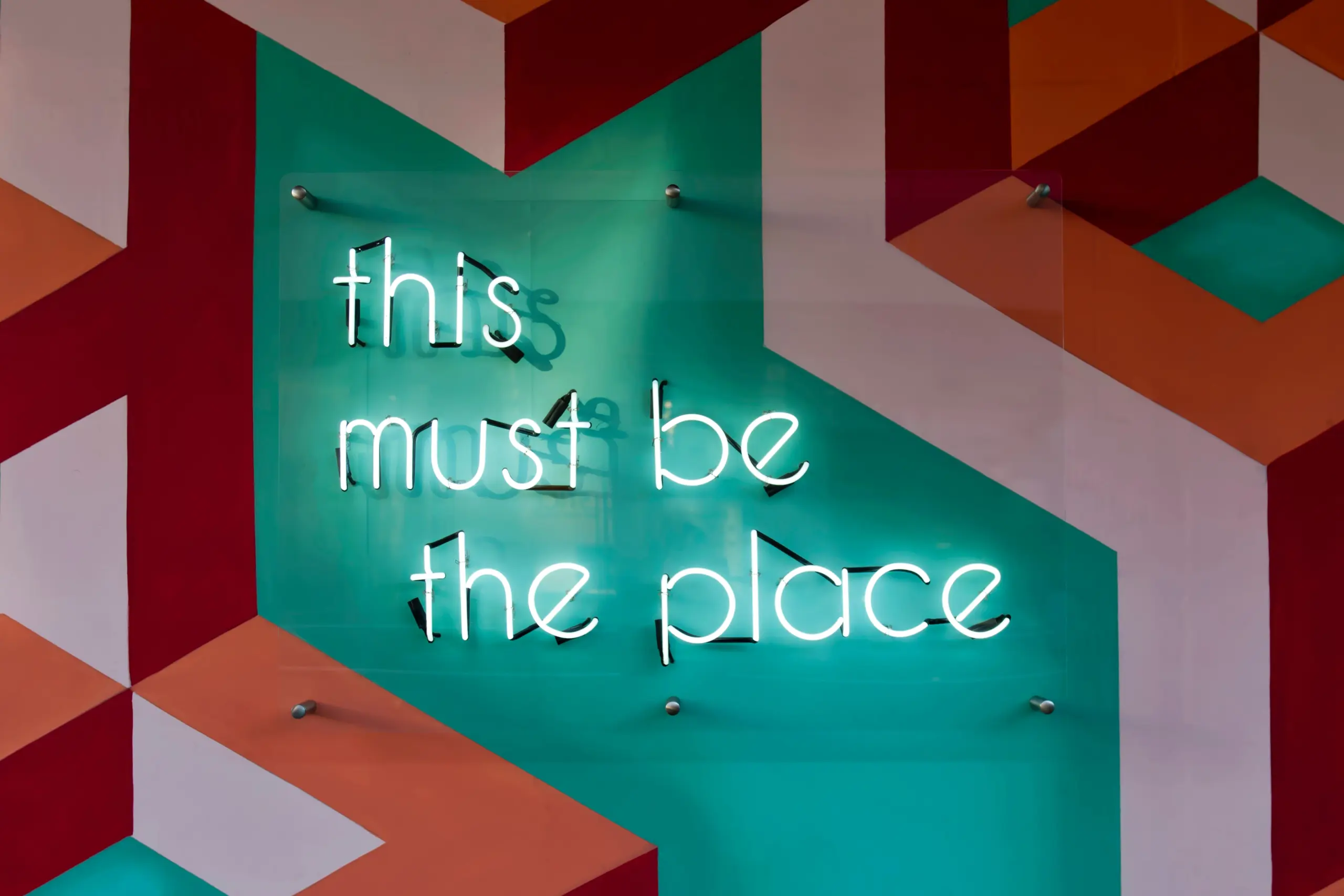 A green neon sign with the phrase "this must be the place" written on it