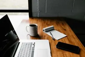 A computer, a notepad and a cup of coffee